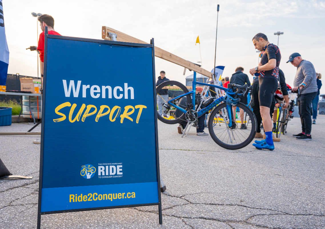 Une station de réparation de vélos avec un panneau « Wrench Support » et des personnes travaillant sur des bicyclettes.