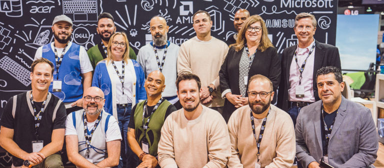 A group of people posing for a photo at a tech event with logos in the background.