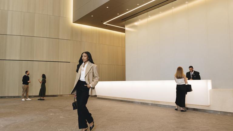 A modern lobby with a reception desk and people interacting.