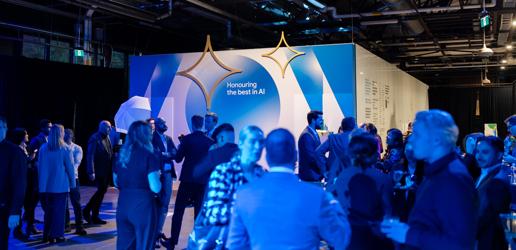 A group of people socializing at an event with a sign that says "Honoring the best in AI."