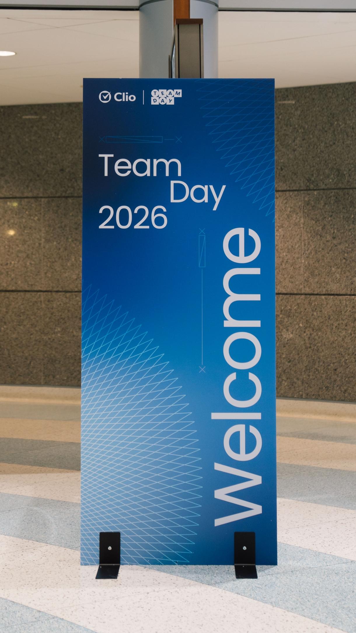 A blue sign with "Team Day 2026" and "Welcome" in white text.