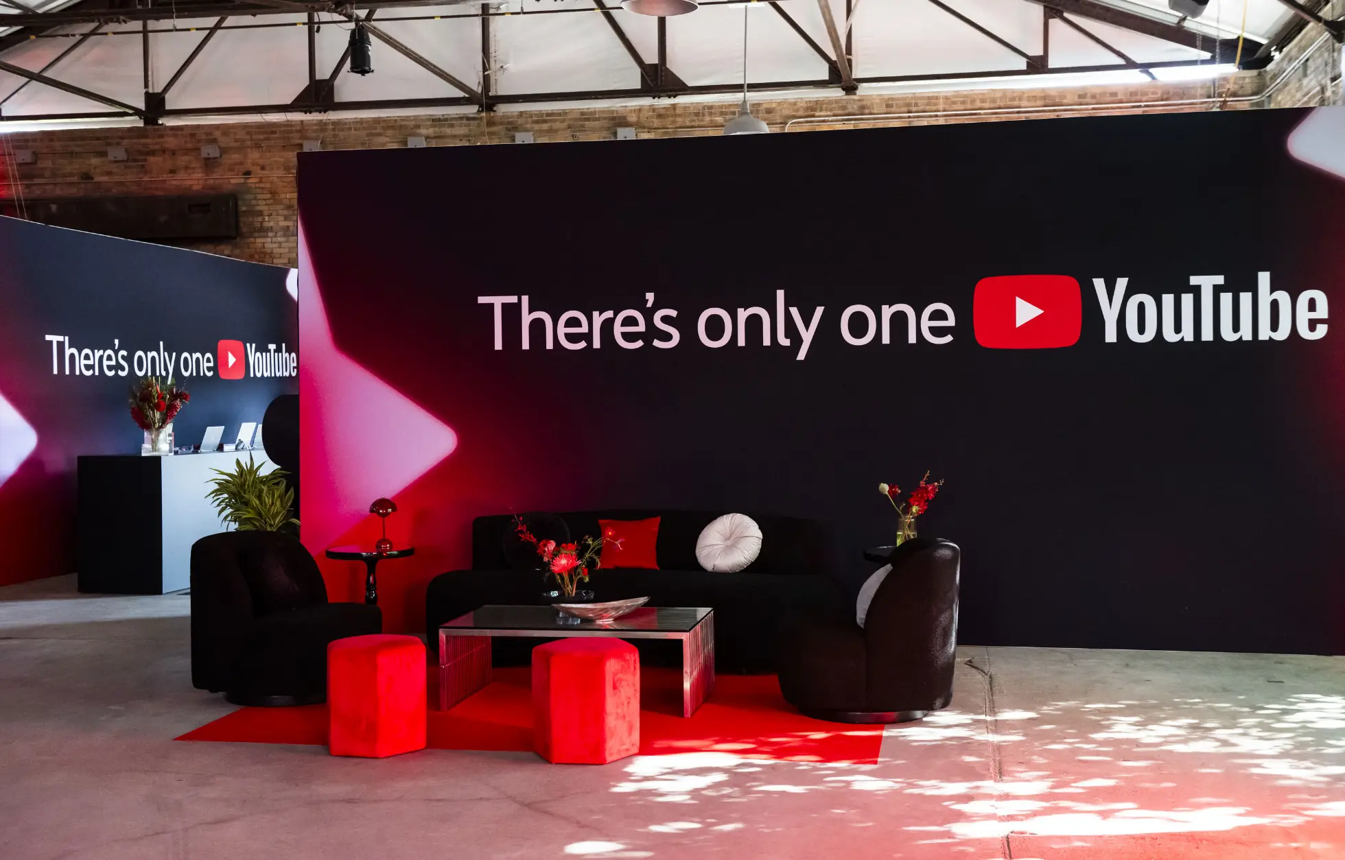 Une pièce avec des canapés noirs, des accents rouges et un grand panneau indiquant « There's only one YouTube » sur le mur.