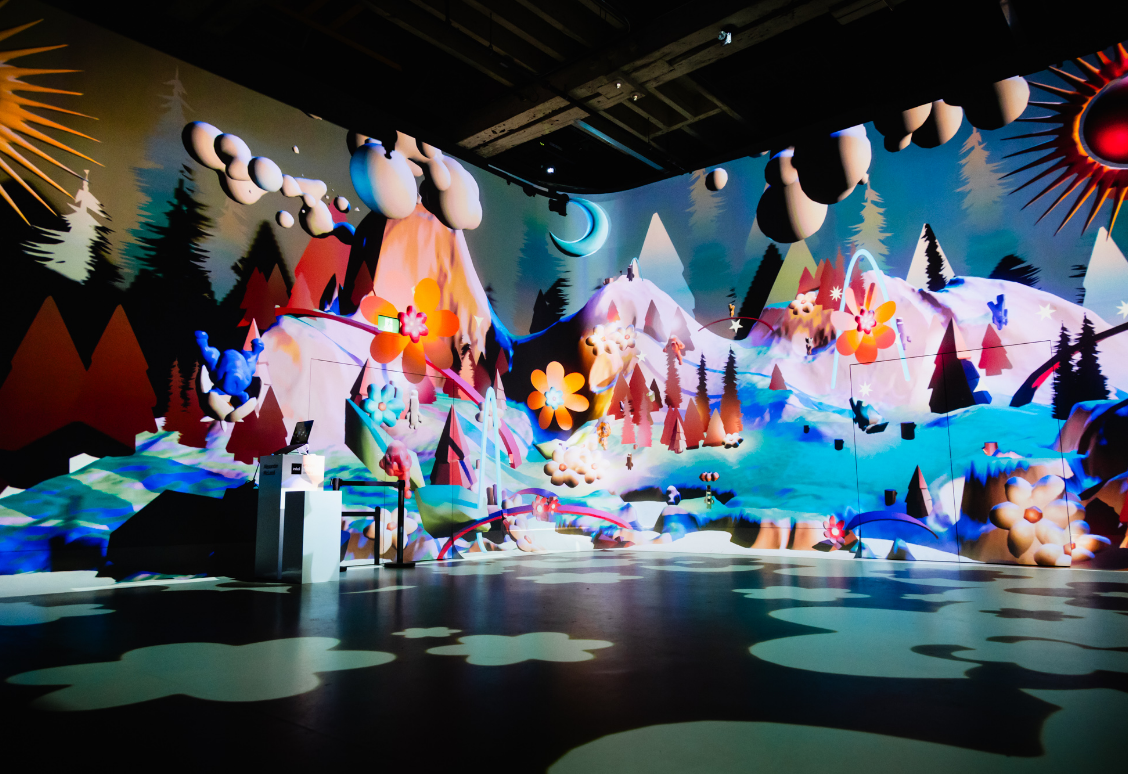 A colorful, whimsical art installation featuring mountains, flowers, and trees with a playful, dreamlike atmosphere.