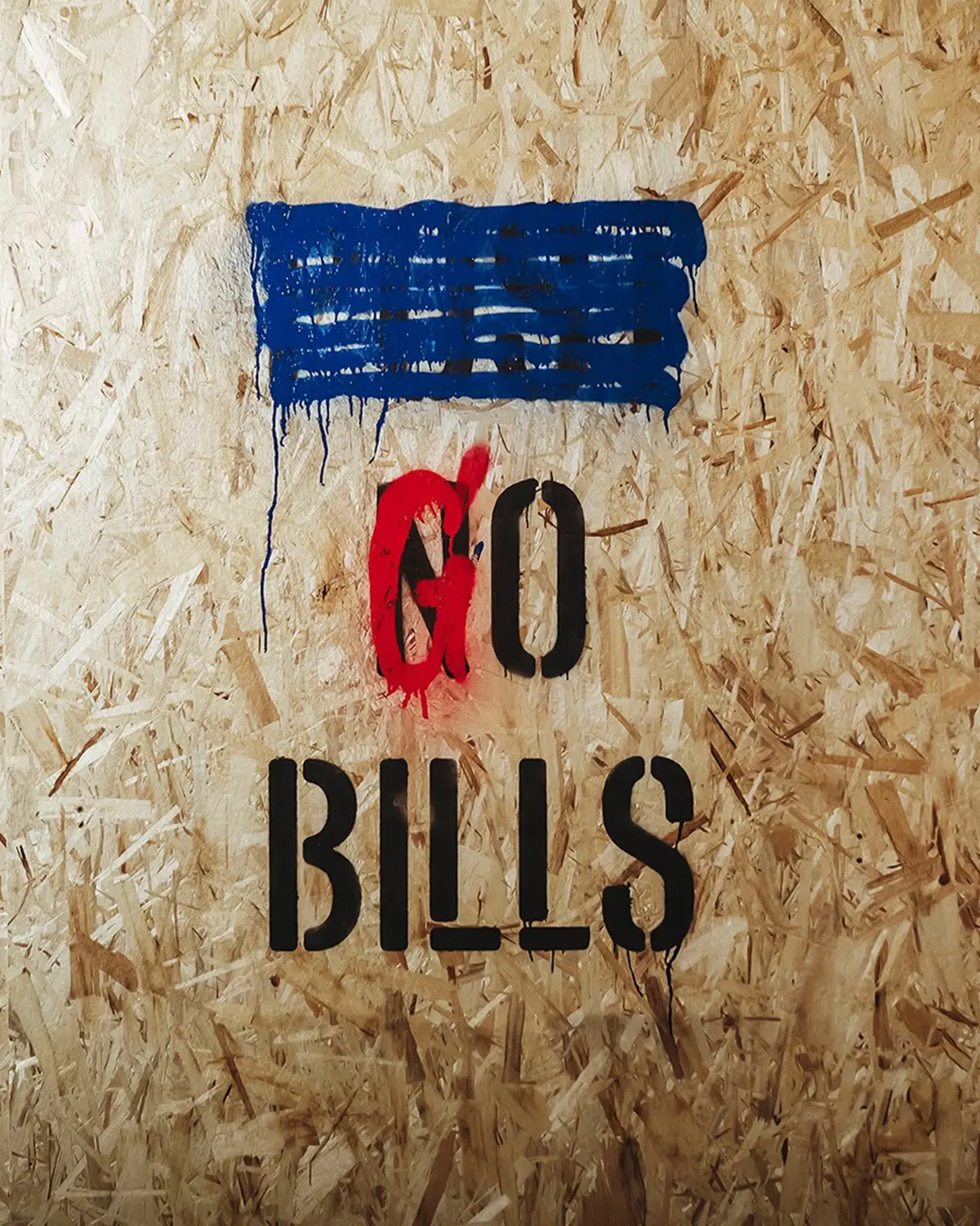 Text reading "GO BILLS" is spray-painted on a textured wood surface with blue and red paint drips above.