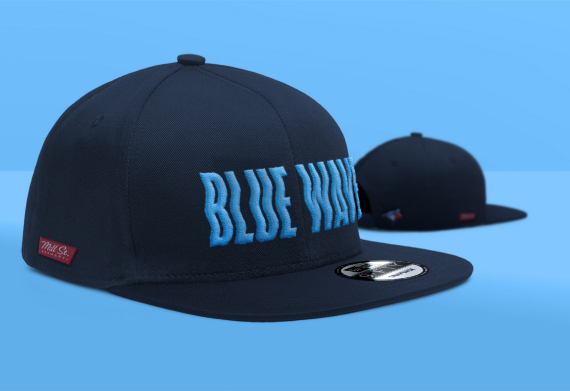 Deux casquettes de baseball bleu marine avec « BLUE WAVE » en lettres bleues, l'une face à l'avant et l'autre à l'envers, sur un fond bleu.