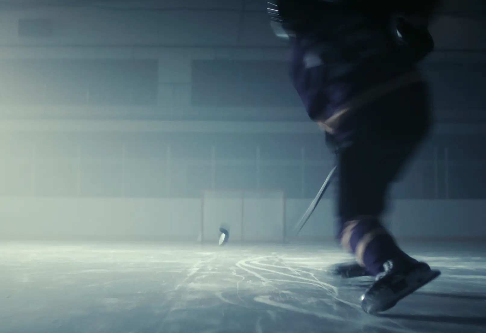Un joueur de hockey patine sur une patinoire, avec une rondelle volant dans les airs vers un but.