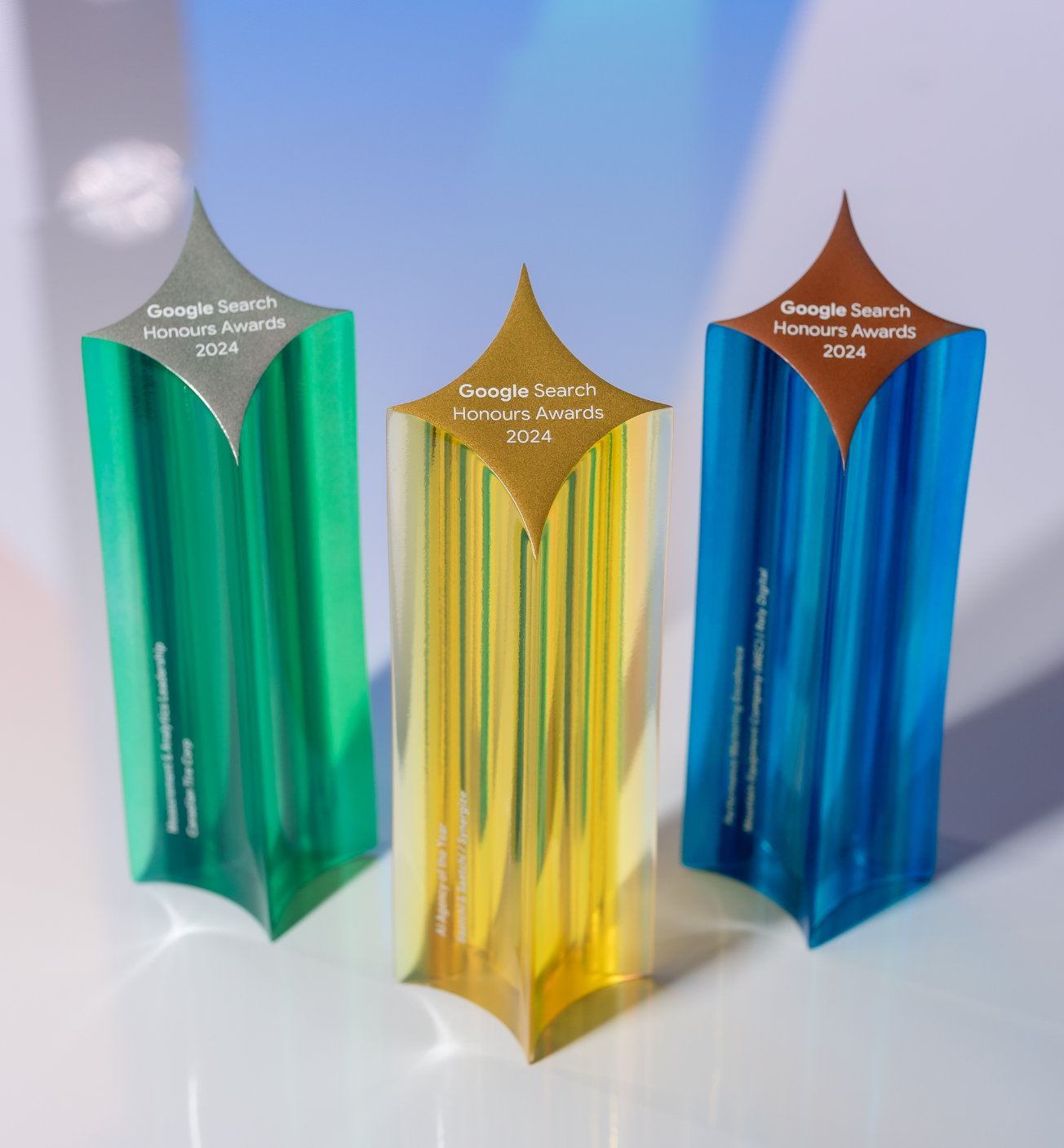Three colorful, star-shaped trophies labeled "Google Search Honours Awards 2024" in green, yellow, and blue.