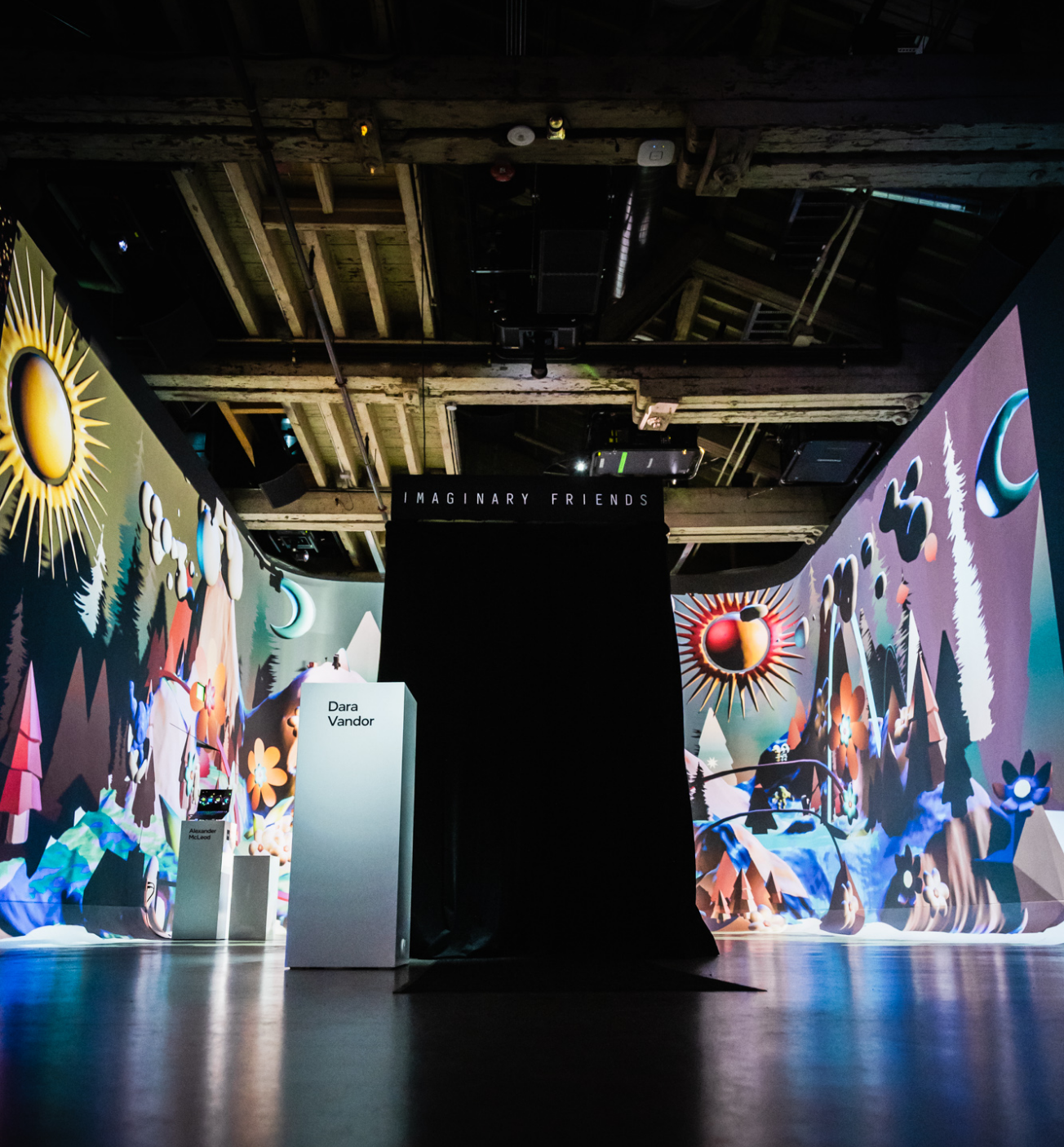 A dimly lit room with colorful, abstract murals featuring a central dark installation labeled "Imaginary Friends."