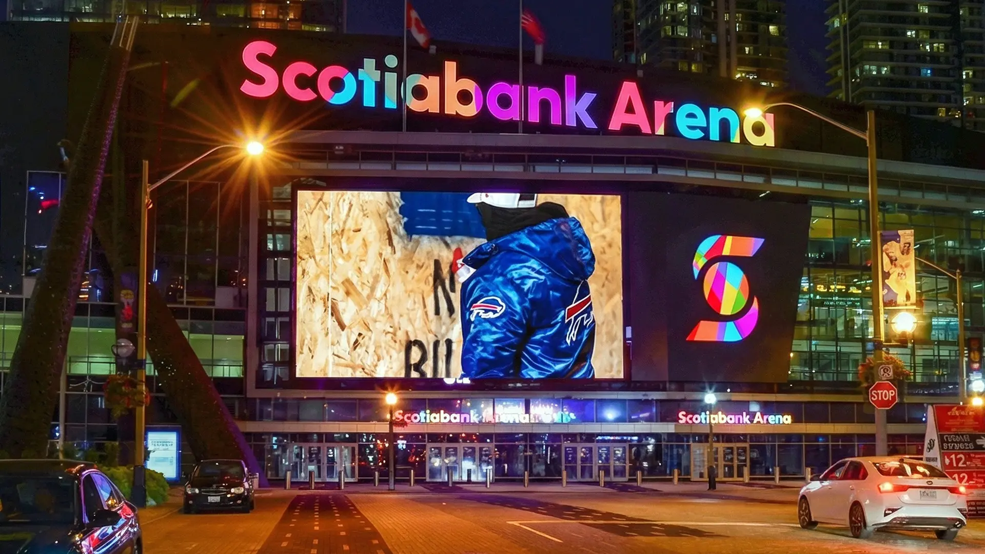 Front entrance of Scotiabank Arena at night with illuminated signage and a large video screen.