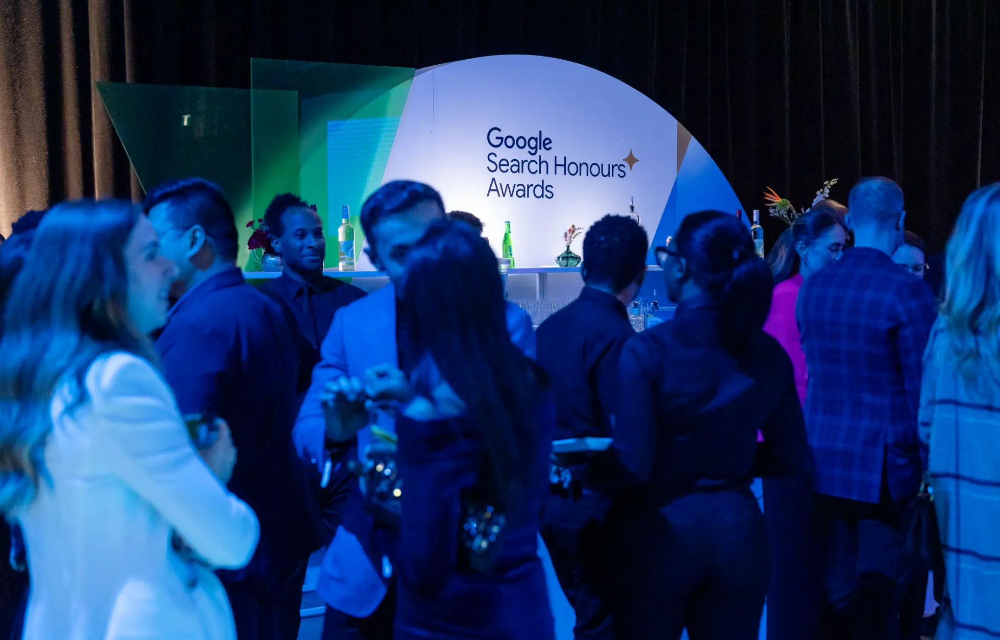 Un groupe de personnes socialisant lors d'un événement avec un panneau indiquant « Google Search Honours Awards » en arrière-plan.