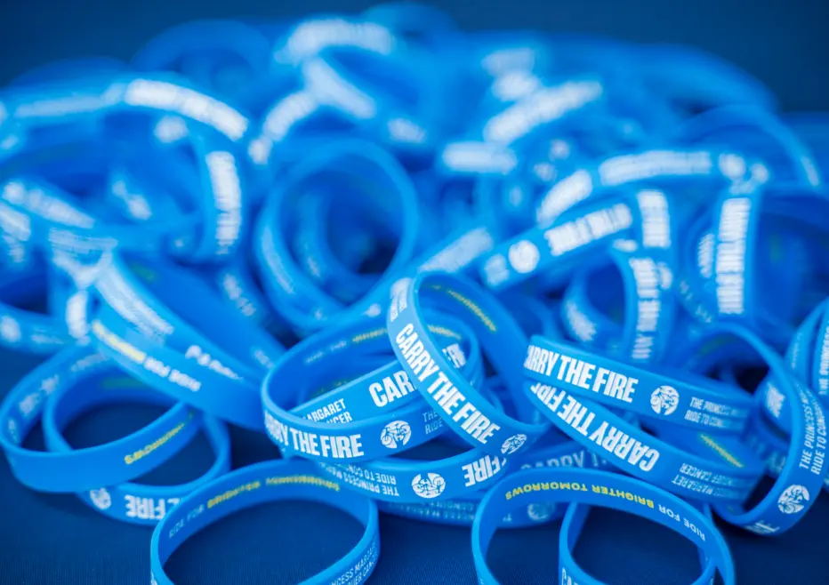 Une pile de bracelets bleus avec « CARRY THE FIRE » imprimé dessus.