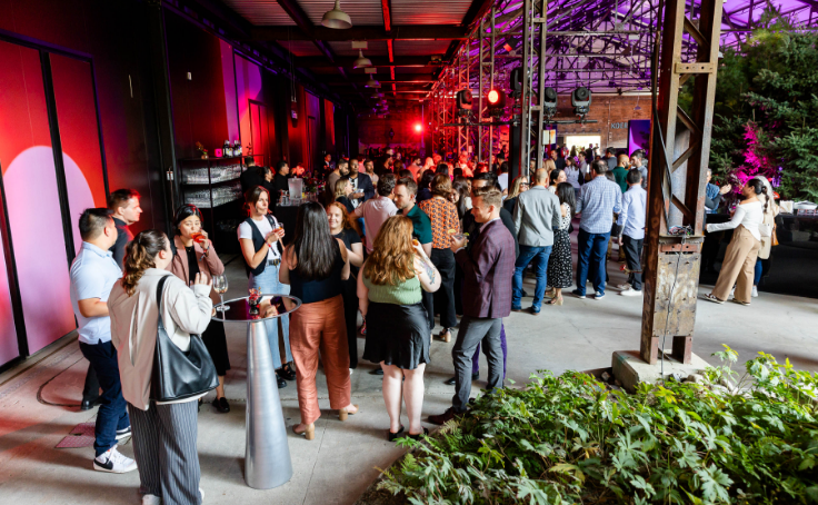 A lively indoor party or event with people socializing and colorful lighting.