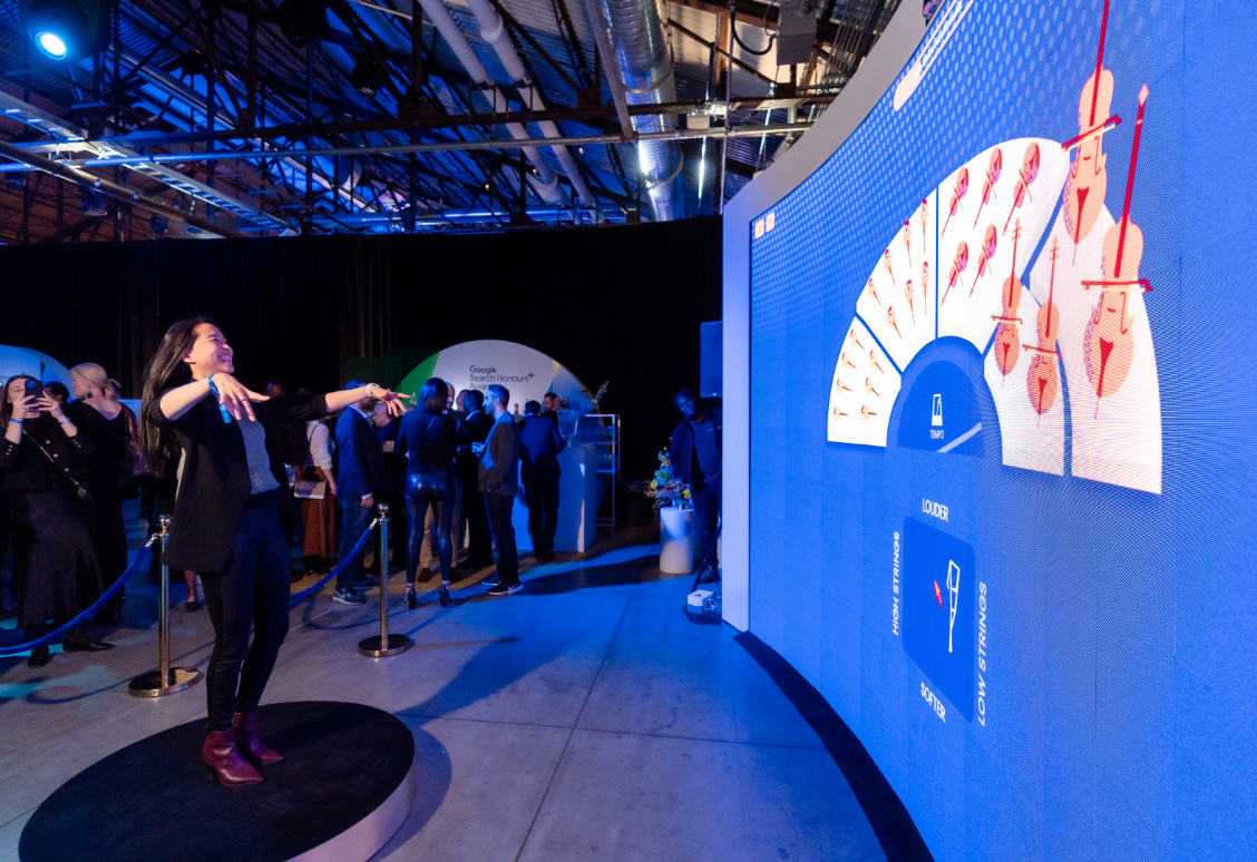 A person stands on a circular platform interacting with a large digital display showing visuals and data.