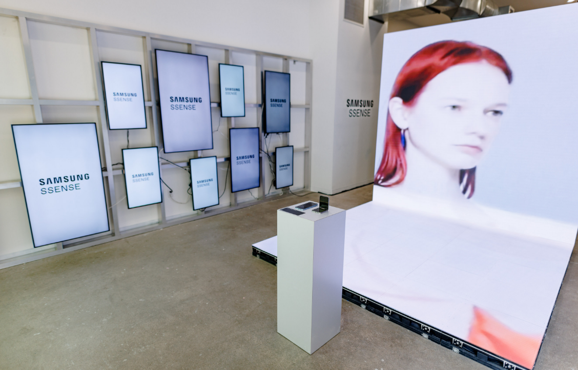 A display area features multiple Samsung screens with logos and a large screen showing a woman with red hair.