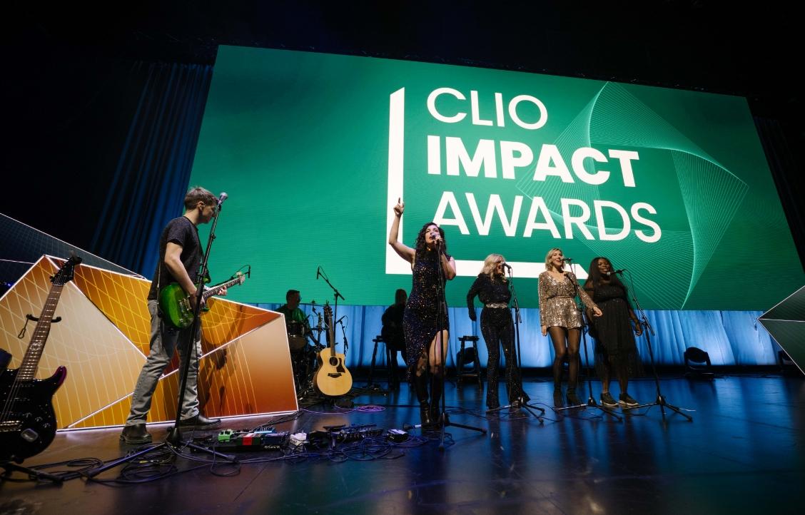 A group of musicians performing on stage at the Clio Impact Awards.