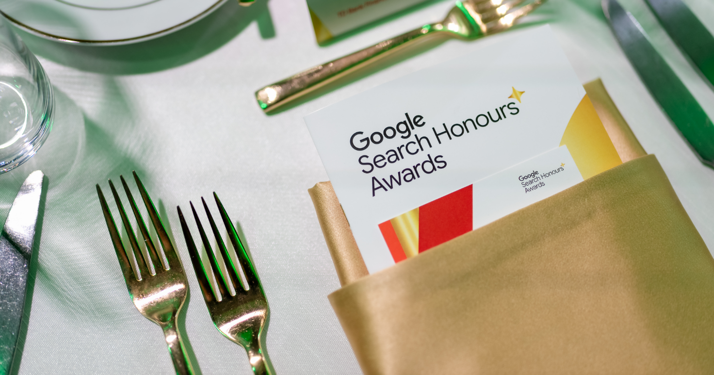 A table setting with cutlery and a program titled "Google Search Honours Awards" in a gold napkin.