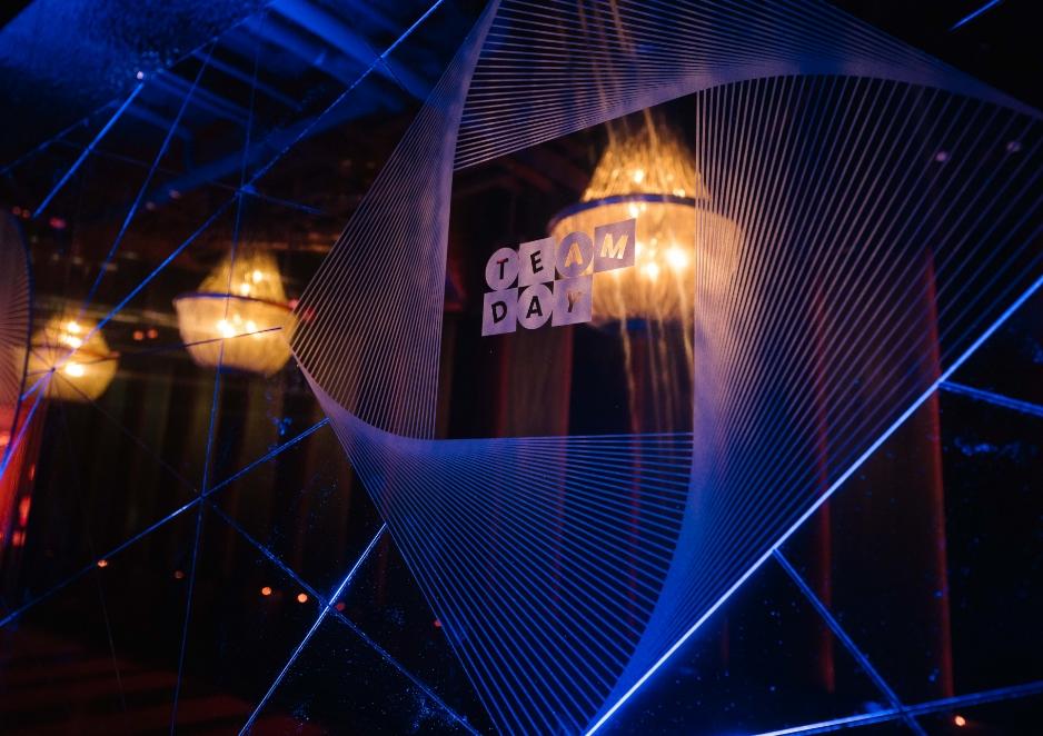 A geometric design with the words "Team Day" reflected on a glass surface under dim lighting.