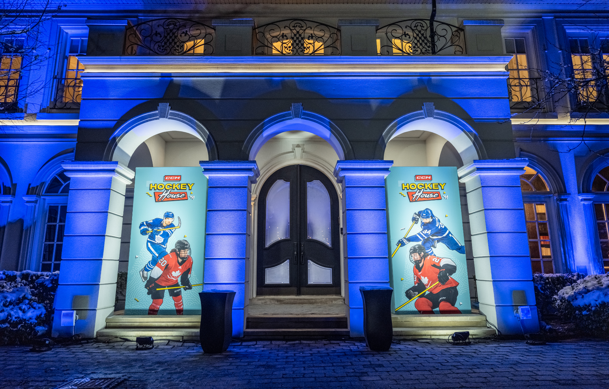 A building entrance illuminated in blue with banners featuring hockey players on either side.