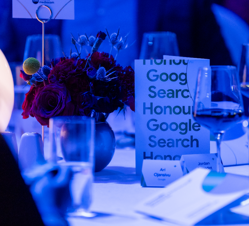Table setting with flowers, glassware, and a program that reads 'Google Search Honour.'